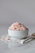 Pink Himalayan salt in the small white bowl and white marble surface