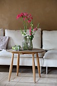 Vases of agapanthus and snapdragons on round wooden table in living room