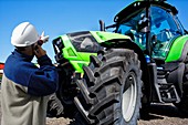 Farmer on the phone pointing at tractor