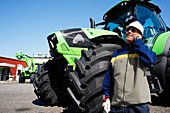 Farmer on the phone in front of tractor