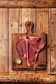 Raw fresh meat T-Bone Steak and weight on cutting board on wooden background