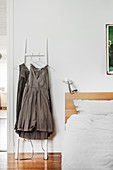 Grey dresses hung from ladder next to bed