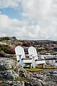 Two wooden loungers on rocks under cloudy sky