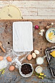 Zutaten für Kuchen (Eier, Blockschokolade, Milch) auf Vintage Untergrund mit Blüten dekoriert