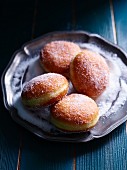 Four jam doughnuts on a pewter plate