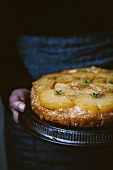A woman holding a pineapple upside down cake