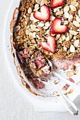 A portion of a large oval bowl of half eaten Strawberry and Rhubarb Breakfast Oat Crisp