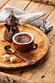 Cup of black coffee and Turkish Cezve on wooden background
