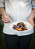 Man holding a plate with lentil and fruit salad
