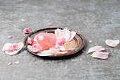 Rose quartz with rose petals on a silver plate