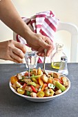 Women mixing ingredients for panzanella salad