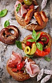 Fried sausages, wienerwurst, ham, marinated chili peppers served in salted pretzels with fresh basil