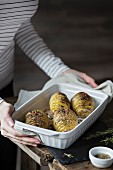 Woman with roasted hasselback potatoes