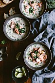 Three bowls of salmon coconut chowder garnished with cilantro and scallions