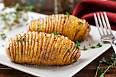 Hasselback potatoes with herbs on a plate
