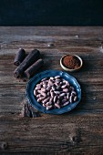 Raw cacao in three different forms, as cacao beans, sticks and powder