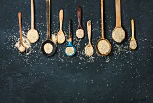 Quinoa seeds in different spoons over black stone background