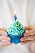 Hands holding birthday cupcake