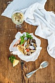 Seafood pasta. Linguine with clams and shrimps in bowl, glass of white wine over rustic wood background