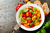Fresh tomatoes with basil leaves in a bowl on vintage background