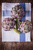 Three purple artichokes on a tea towel
