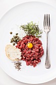 Beef tartare with capers and fresh onions on white background