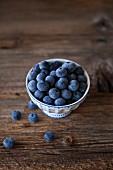 Blueberries in a small bowl on a rustic wooden table