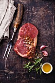Rohes Ribeye Steak mit Gewürzen und Fleischgabel auf Metalluntergrund