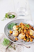Fried chanterelles with potatoes and onion on white wooden background