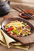 Asian yakisoba noodle with fried vegetables and omelette on a wooden plate