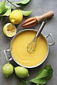 Lemon curd in a pan with fresh lemons