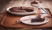 Tray of fudgy brownies with one slice on separate plate