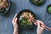 Chicken stir fry with roasted broccoli, hands with chopsticks