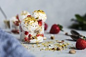 A couple scoops of coconut milk and cashew ice cream topped off with strawberries and pistachio crumbs