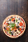 Pizza with mushrooms and ruccola on wooden table