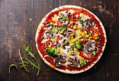 Vegetarian pizza with mushrooms and ruccola on wooden table