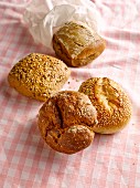 Four fresh bread rolls on a checked tea towel