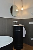 Modernisiertes Bad mit grauer Wandverkleidung, rundem Spiegel und schwarzem Waschbeckenmöbel