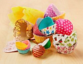Various types and colours of cupcake and muffin cases on a wooden surface
