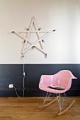 Pink rocking chair in front of star with lightbulbs on two-tone wall
