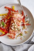 Bacon-wrapped hake with red and yellow pepper strips and cucumber salsa