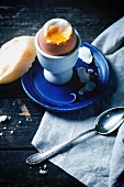 Breakfast with soft-boiled egg, served with bread over old wooden table