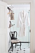 Dressing gown hung on wall of shower above old chair