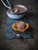 Chocolate icecream and scoop with walnut cornet on slate board on wooden table