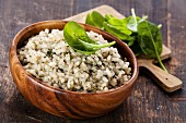 Risotto with spinach in wooden bowl