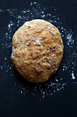 Frisch gebackenes Brot mit Mehl vor dunklem Hintergrund (Aufsicht)