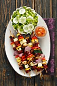 Sausage and vegetable skewers with cucumber salad (seen from above)