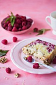 A slice of a cake with raspberries on a pink plate