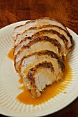 Turkey sliced with gravy on a white plate on a rustic table