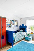 Blau gestrichenes antikes Bett im Kinderzimmer mit blauem Teppich